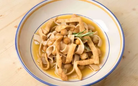 Un piatto di ciceri e tria, pasta fresca con ceci e sfoglie fritte, guarnito con rosmarino.