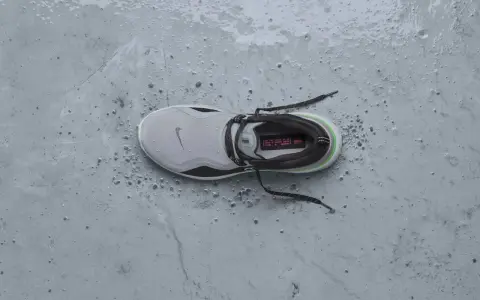 Zapatilla Nike gris con detalles verdes y negros, mojada y con gotas de agua. ¡Perfecta para que se puedan meter las zapatillas en la secadora sin problema!