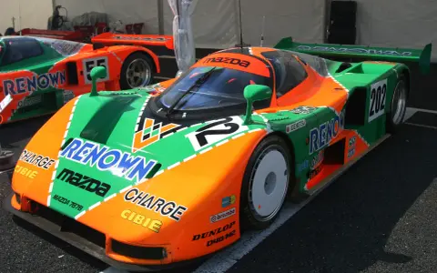 El icónico Mazda 787B, con su distintivo diseño naranja y verde, listo para la carrera.