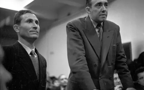 Deux hommes en costume, dont Gustave Dominici, se tiennent debout dans une salle.
