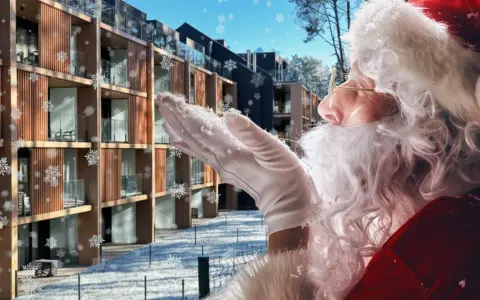 Śnieżynki tańczą wokół Świętego Mikołaja dmuchającego śniegiem na nowoczesny hotel. Czas na mikołajki w hotelu!