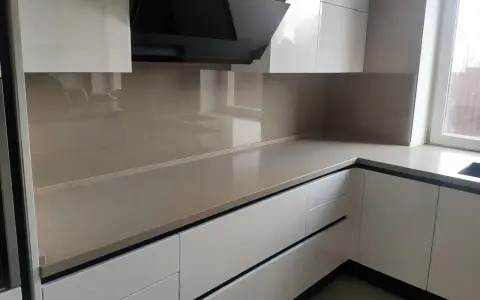 Nowoczesna kuchnia z frontami w kolorze ral9001 i eleganckim, jasnym blatem. Czarny okap dodaje charakteru.