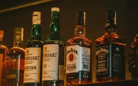 Rząd butelek whisky: Laphroaig, Jim Beam i Jack Daniel's.