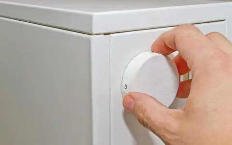 Hand dreht den Regler einer alten Nachtspeicherheizung. Die Bedienung ist einfach, die Zahlen sind gut sichtbar.