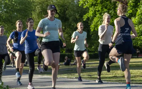 Grupp kvinnor tränar löpning i parken, ett intensivt backintervaller pass.