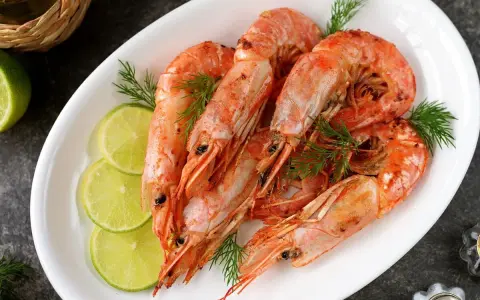 Plato blanco con langostinos cocidos, rodajas de limón y eneldo. Ideal para recetas con langostinos.