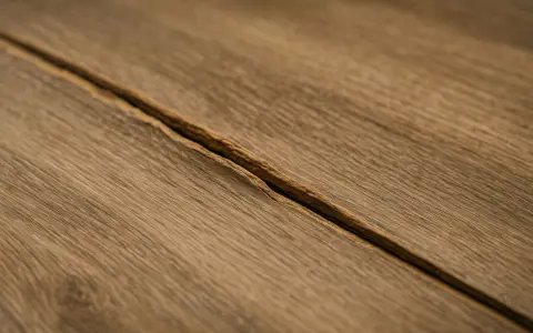 Widoczne pęknięcie na drewnianych panelach, które wyglądają jakby były zalane na łączeniach.
