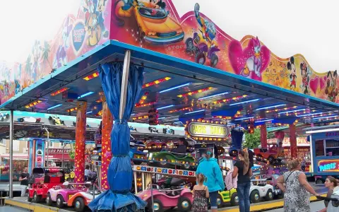 Attraction for children with cars, decorated with Mickey Mouse and friends. A sign says "Paris Dakar".