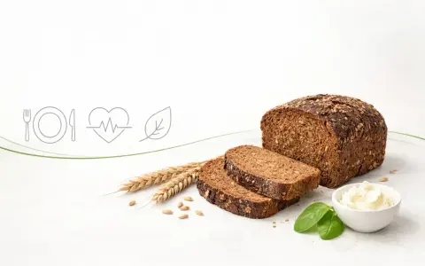 Chleb razowy z ziarnami, obok kłosów i masła. Zastanawiasz się, ile kcal ma chleb razowy? To zdrowy wybór!