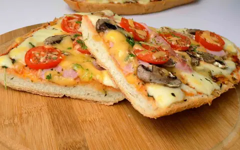 Dwie pyszne pizze na bagietce z pomidorami, pieczarkami i serem. Idealne na szybki obiad.