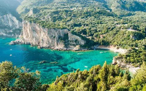 Baia verde smeraldo a Corfu, perfetta per una vacanza con bambini. Scogliere imponenti e acque cristalline invitano al gioco e all'esplorazione.