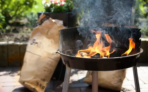 Ogień płonie w grillu, a obok leżą worki z węglem. Czas dowiedzieć się, jak rozpalic grilla i cieszyć się smakiem lata!
