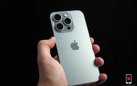 Dłoń trzyma srebrny iPhone 15 Pro z widocznym modułem aparatów i logo Apple. Dynamic Island na ekranie tego modelu to innowacja.