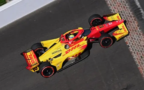 Alex Palou, piloto del coche número 10, acelera en la pista con su monoplaza amarillo y rojo de DHL.