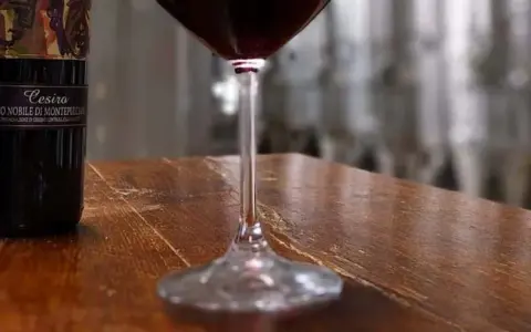 Bottiglie di Vino Nobile di Montepulciano e un calice di vino rosso, pronti per una degustazione vini toscana.