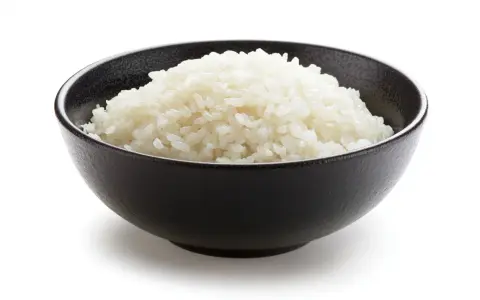 Un tazón negro lleno de arroz blanco esponjoso, listo para ser parte de un delicioso arroz frito.