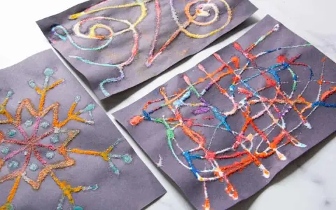 Kinder malen auf schwarzem Papier mit bunten Salzkristallen. Ein Bild zeigt eine Schneeflocke, die anderen abstrakte Muster.