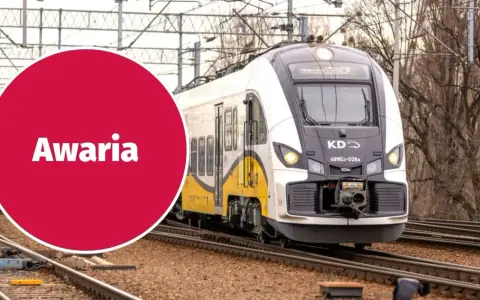 Pociąg KD stoi na torach, a czerwone koło z napisem "Awaria" sugeruje problem z zasilaniem, być może zerwana sieć trakcyjna.