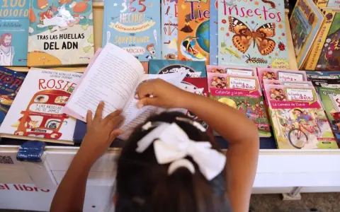 Niña lee libros sobre cuentos de igualdad de género, rodeada de coloridas portadas que inspiran a la imaginación.