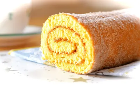 En saftig glutenfri rulltårta med socker strött över, perfekt för fikat.