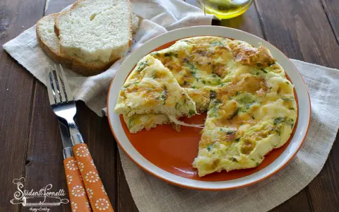 Una soffice frittata di albumi con erbe aromatiche, servita su un piatto arancione, accanto a fette di pane tostato e una forchetta.