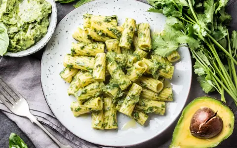Pyszny makaron z pesto, podany z awokado i świeżymi ziołami. Idealny na szybki obiad.
