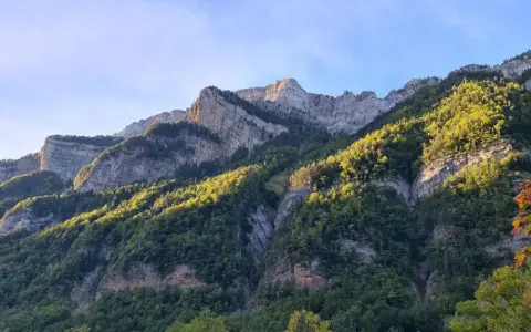 Majestuosas montañas cubiertas de bosque verde y rocas, perfectas para **rutas por Ordesa** en un día soleado.