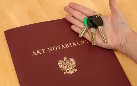 Akt notarialny i klucze na dłoni – symbol finalizacji transakcji. Komparycja dokumentu i symbolu własności.
