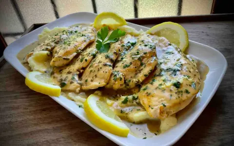 Delicioso pollo al limón con puré de patatas, adornado con rodajas de limón y perejil fresco.