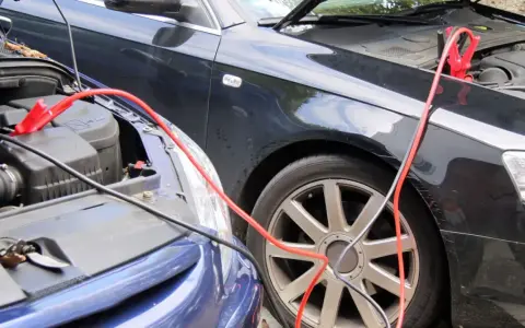 Zwei Autos werden mit Starthilfekabeln verbunden, um die Batterie zu starten.