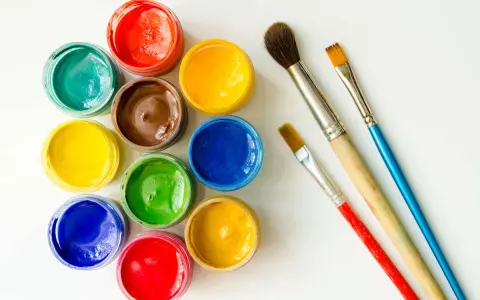 Tarros de temperas de colores vibrantes y pinceles listos para pintar.