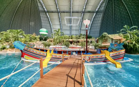 Kolorowy statek z żółtymi zjeżdżalniami w tropikalnym basenie. Idealne miejsce na wakacje, sprawdź bilety na tropical islands!