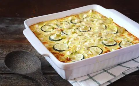 Un délicieux gratin de courgettes, prêt à être dégusté, avec des rondelles de courgettes et des morceaux de poireau dans une sauce crémeuse.