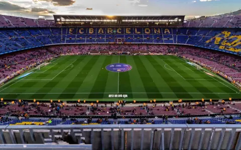 Widok na stadion Camp Nou podczas remontu, z trybunami w kolorach FC Barcelony i oświetlonym boiskiem.