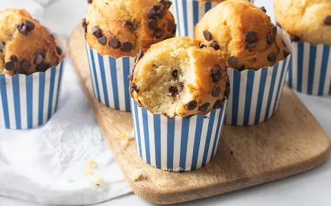 Muffin in friggitrice ad aria con gocce di cioccolato, uno è stato morso rivelando un interno soffice.