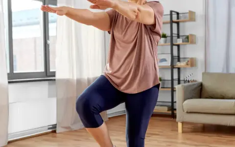 Frau macht Oberschenkel Training ohne Kniebelastung. Sie steht auf einem Bein, das andere angewinkelt.