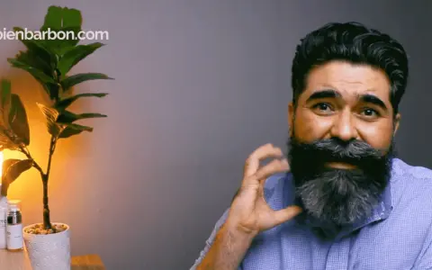 Hombre con una barba corta y cuadrada, peinada con estilo. A su lado, una planta y productos de cuidado personal.