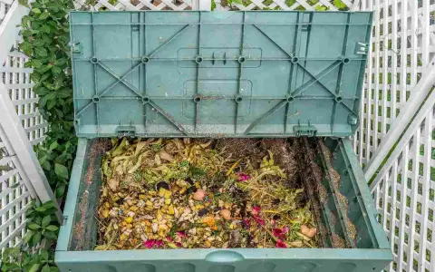 Compostiera verde piena di scarti organici, un esempio di bokashi fai da te per un giardino sostenibile.