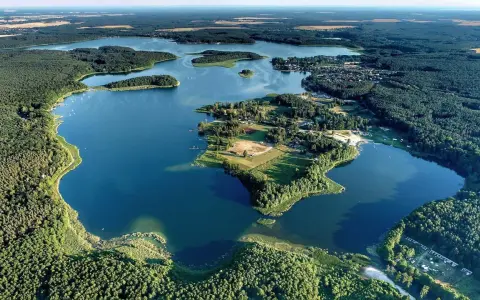 Malownicze jezioro Niesulice otoczone lasami, z wyspami i zabudowaniami na brzegu. Idealne miejsce na wypoczynek.