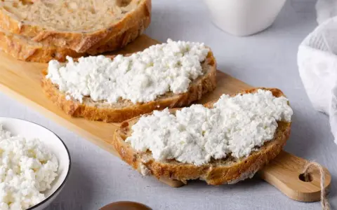 Fette di pane rustico con abbondante ricotta fresca, pronte per gustose ricette con ricotta.