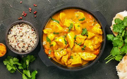 Kurczak w sosie curry z ryżem, kolendrą i pieczywem.