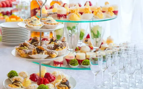 Un buffet de hors d'œuvre varié avec des mini-tartes, des éclairs au chocolat et des fruits frais, prêt à ravir les invités.