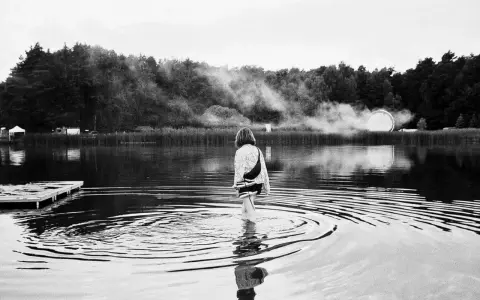 Ein Mädchen watet im Wasser, während im Hintergrund Nebel und eine Lichtinstallation zu sehen sind. Ein friedlicher Moment beim nachtigall festival.
