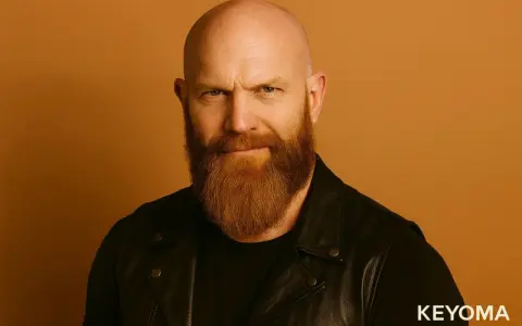 Hombre calvo con barba vikinga, mirada intensa y chaqueta de cuero.