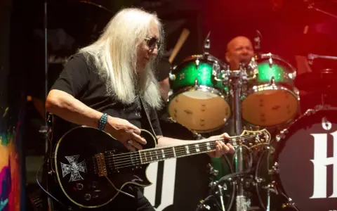Uriah Heep członkowie na scenie. Mick Box gra na gitarze, a za nim perkusista.