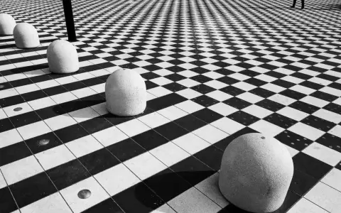 Massi ovali su pavimento a scacchi, un gioco di prospettiva e ombre. #streetphotography