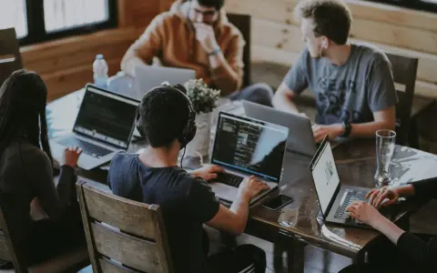 Un grupo de personas trabaja en sus portátiles en una mesa. Uno de ellos, con auriculares, parece concentrado en su pantalla, quizás buscando la clave del modelo 190.