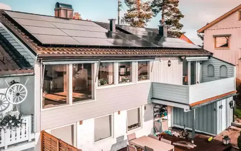 Hus med trina solceller på taket. En balkong med blommor och ett dekorativt hjul.