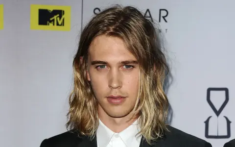 Austin Butler z długimi, falowanymi włosami, który udowadnia, komu pasują długie włosy męskie.
