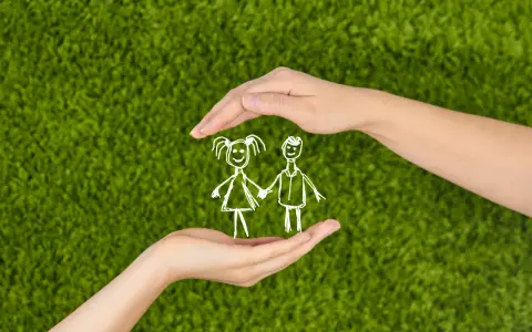 Hände schützen Kinderzeichnung auf grünem Rasen. Wichtige Aspekte für eine Kindeswohlgefährdung Checkliste.
